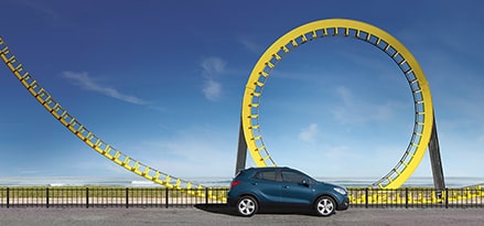 A blue car in front of a yellow rollercoaster